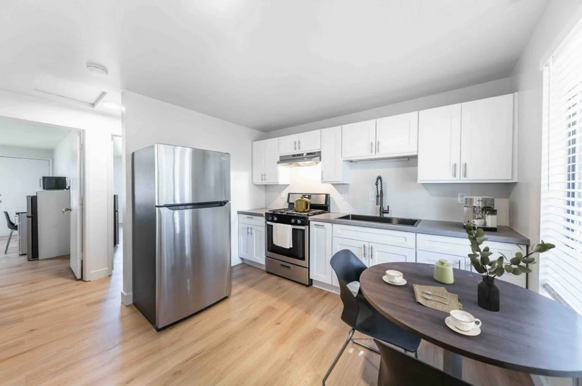 Renovated unit interior — modernized kitchen with white cabinetry and stainless appliances